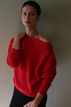 Load image into Gallery viewer, A person wearing an off-the-shoulder Ballerina’s Cashmere Sweater in Vermillion, featuring a relaxed silhouette.