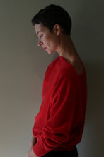 Load image into Gallery viewer, A person with short hair wearing a vibrant red Ballerina’s Cashmere Sweater | Vermillion in a relaxed silhouette.