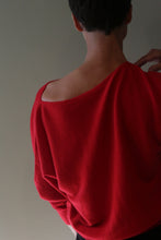 Load image into Gallery viewer, A person viewed from the back wearing a Ballerina’s Cashmere Sweater | Vermillion, featuring a red, relaxed silhouette and a wide, open neckline.