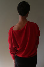 Load image into Gallery viewer, A person seen from behind wearing the Ballerina’s Cashmere Sweater | Vermillion, featuring a relaxed silhouette and an off-the-shoulder neckline.