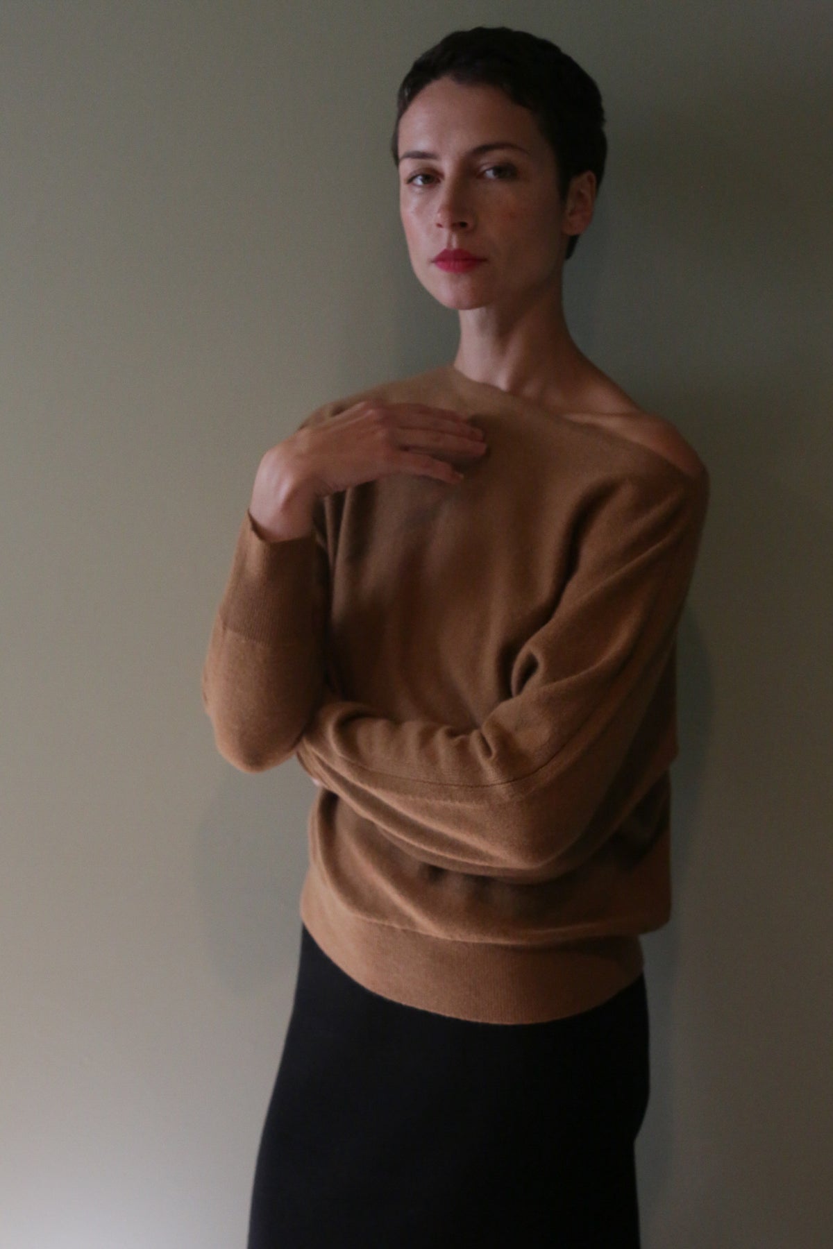 A person with short hair wearing a tan, off-the-shoulder Ballerina’s Cashmere Sweater | Vicuna with a relaxed silhouette.