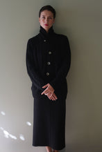 Load image into Gallery viewer, A person wearing a black Unisex Shawl-Collar Cable-Knit Cashmere Cardigan over a matching black skirt.