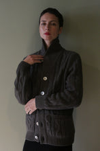 Load image into Gallery viewer, A person wearing a Unisex Shawl-Collar Cable-Knit Cashmere Cardigan in taupe, featuring a shawl collar, cable-knit texture, and large buttons.