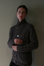 Load image into Gallery viewer, A person wearing a Unisex Shawl-Collar Cable-Knit Cashmere Cardigan | Taupe, a dark brown shawl-collar cashmere cardigan with a cable-knit texture and large white buttons.