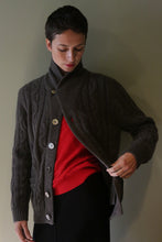 Load image into Gallery viewer, A person wearing a Unisex Shawl-Collar Cable-Knit Cashmere Cardigan | Taupe over a bright red sweater.