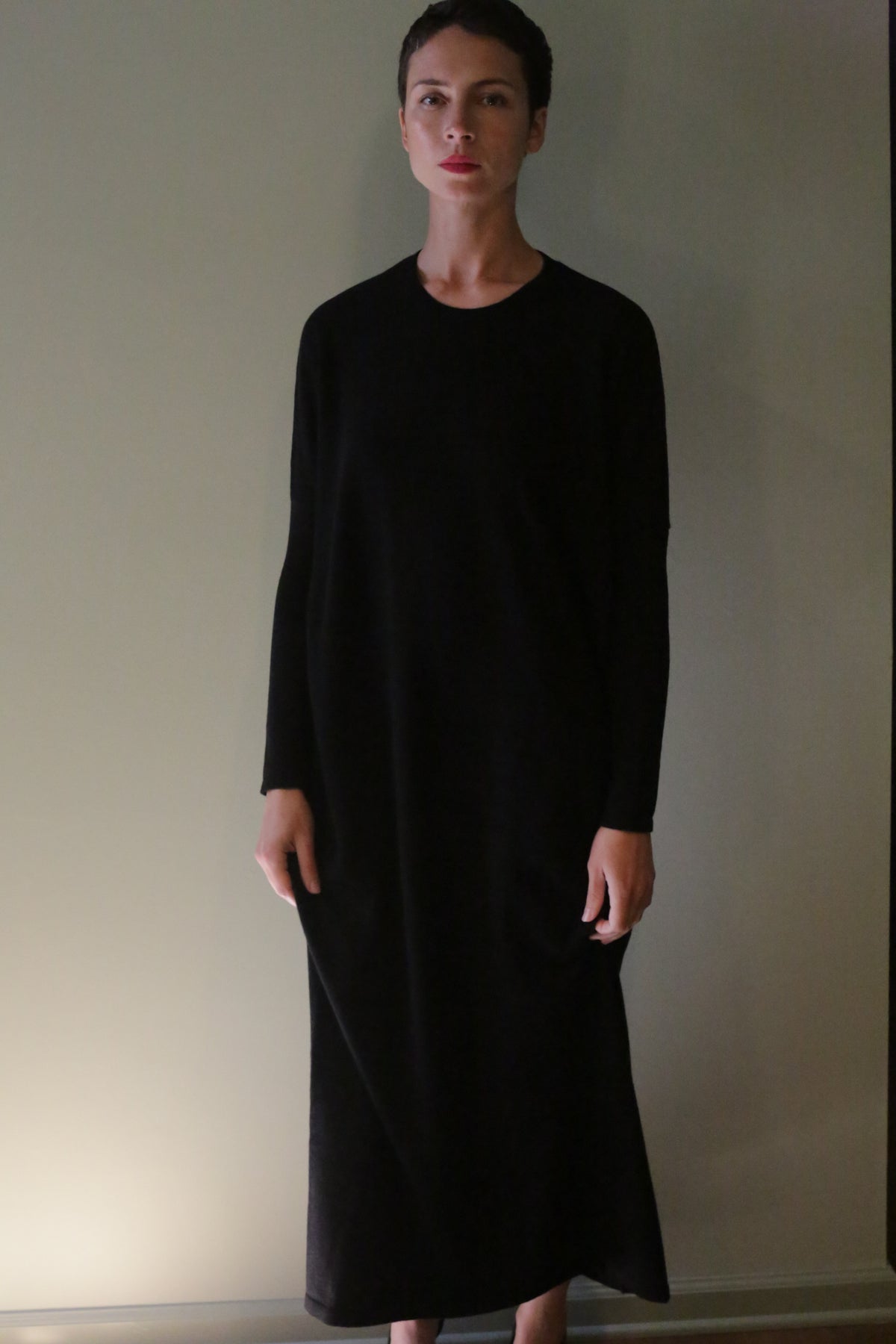 A person wearing a long-sleeved, ankle-length black Cashmere Sweater Dress.