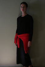 Load image into Gallery viewer, A person wearing a long-sleeved black Cashmere Sweater Dress with a bright red sweater tied around their waist.