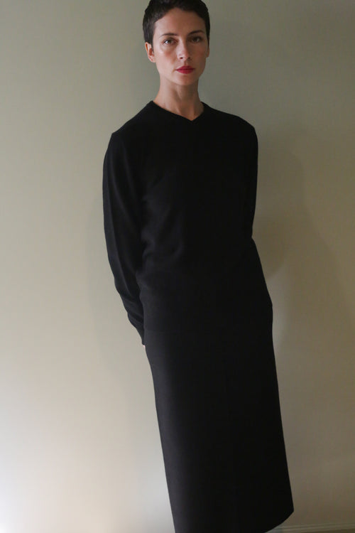 A person wearing a black long-sleeved sweater and a matching Cashmere Pencil Skirt | Black.