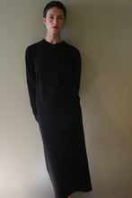 Load image into Gallery viewer, A person wearing a black long-sleeved top and a matching Cashmere Pencil Skirt | Black standing against a plain wall.