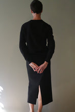 Load image into Gallery viewer, A person seen from behind, wearing a black long-sleeved top and a matching Cashmere Pencil Skirt | Black with a back slit.