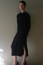 Load image into Gallery viewer, A person wearing a long-sleeved black top and a matching Cashmere Pencil Skirt | Black with a high-waisted fit and side slit.