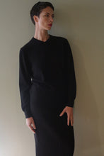 Load image into Gallery viewer, A person wearing a High V-Neck Cashmere Sweater in black and a matching skirt.