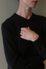 Load image into Gallery viewer, A person wearing a High V-Neck Cashmere Sweater | Black, featuring a long-sleeved design with a high V-neckline.