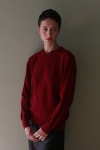 Load image into Gallery viewer, A person with a short haircut wearing a long-sleeved High V-Neck Cashmere Sweater in burgundy.