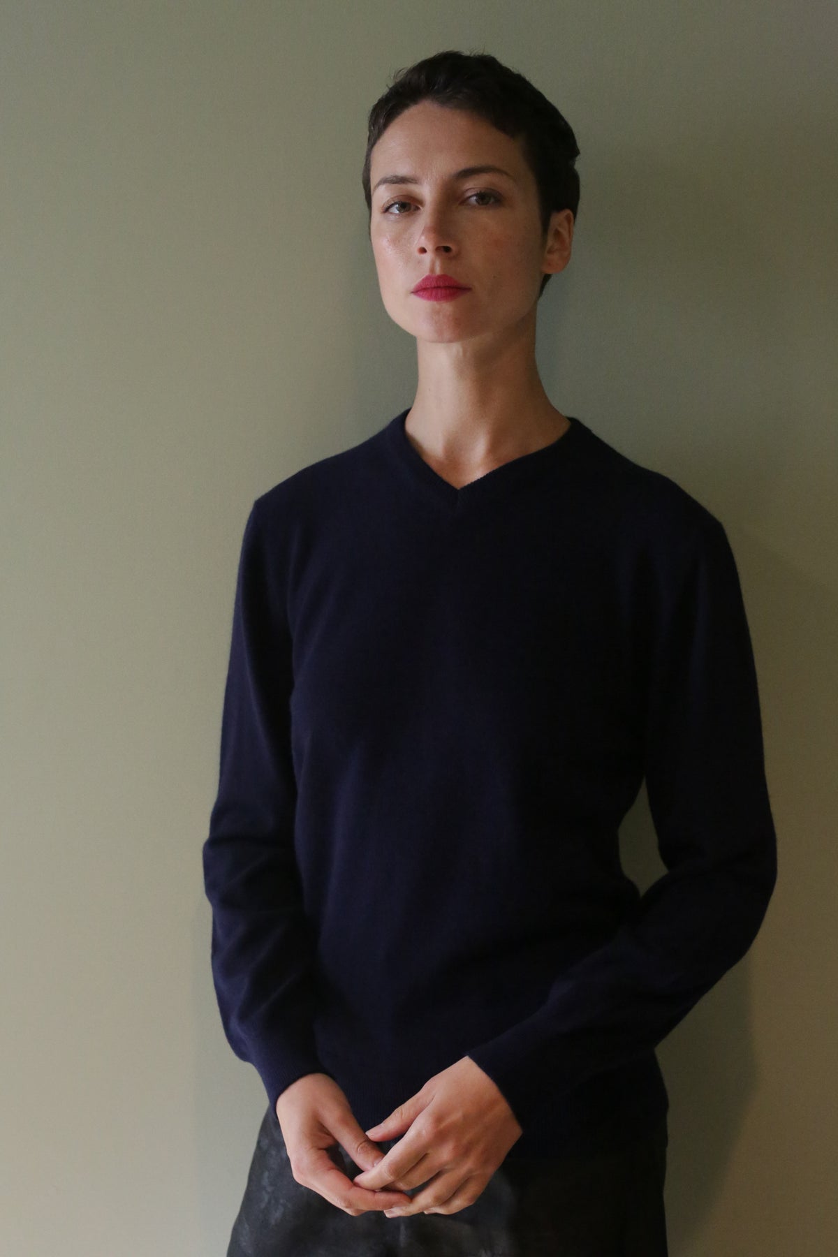A person wearing a navy High V-Neck Cashmere Sweater with a high V-neckline.