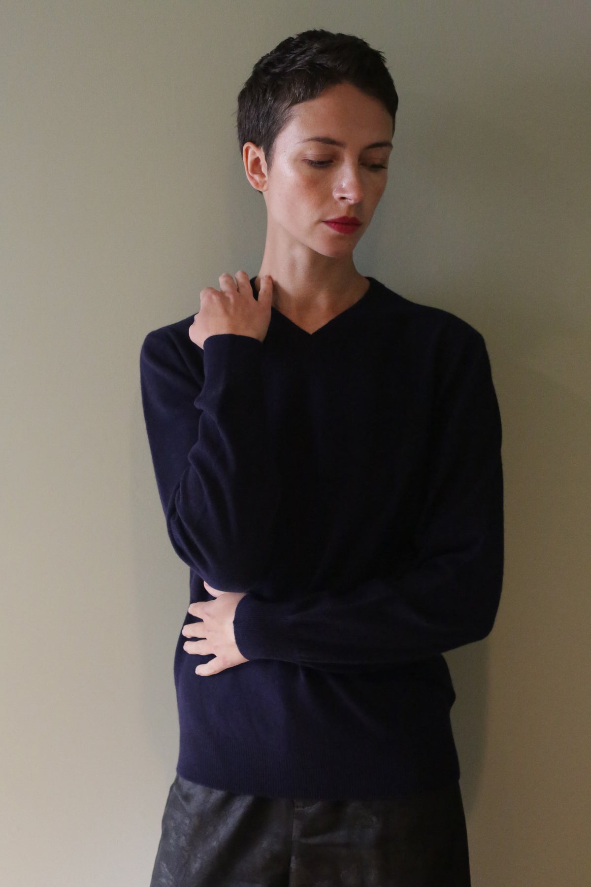 A person wearing a navy High V-Neck Cashmere Sweater with long sleeves.