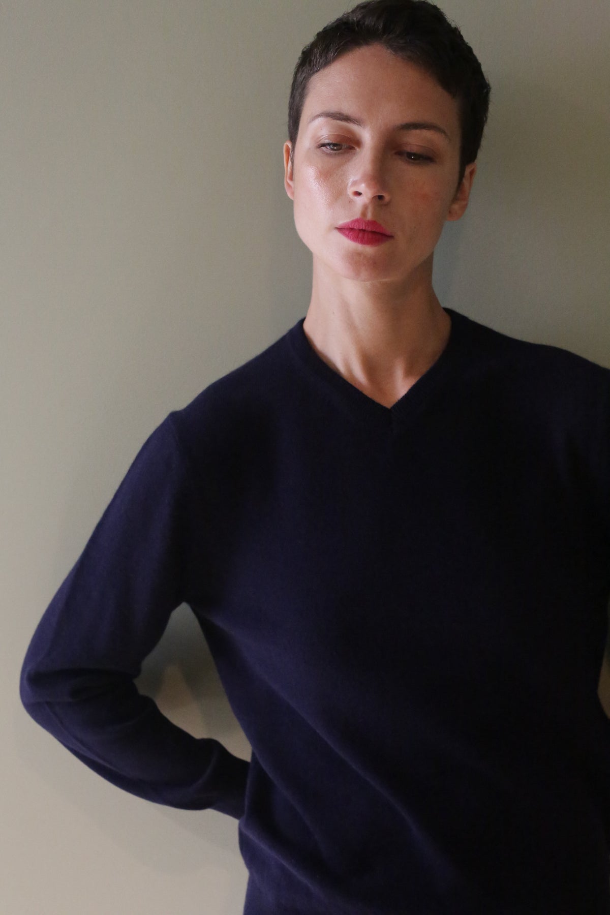 A person wearing a long-sleeved, high V-neck navy blue cashmere sweater.