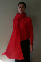 Load image into Gallery viewer, A person wearing a bright red sweater and a matching Tissue Weight Cashmere Scarf | Vermillion draped around their neck with one long end hanging down.