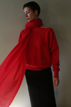 Load image into Gallery viewer, A person wears a vermillion Tissue Weight Cashmere Scarf draped over a matching long-sleeved sweater and a black skirt.