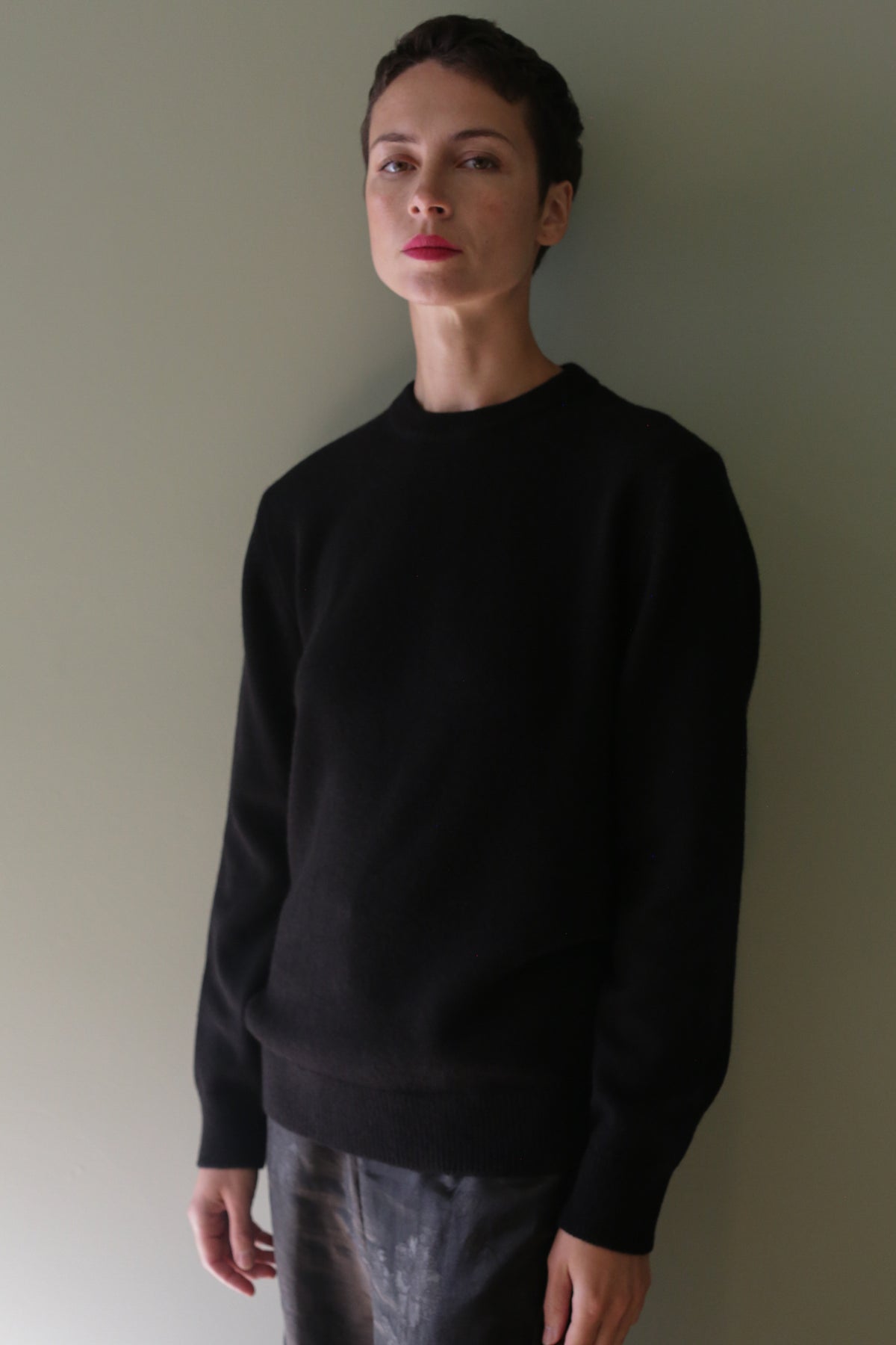 A person wearing a black Unisex Heavyweight Cashmere Crewneck sweater.