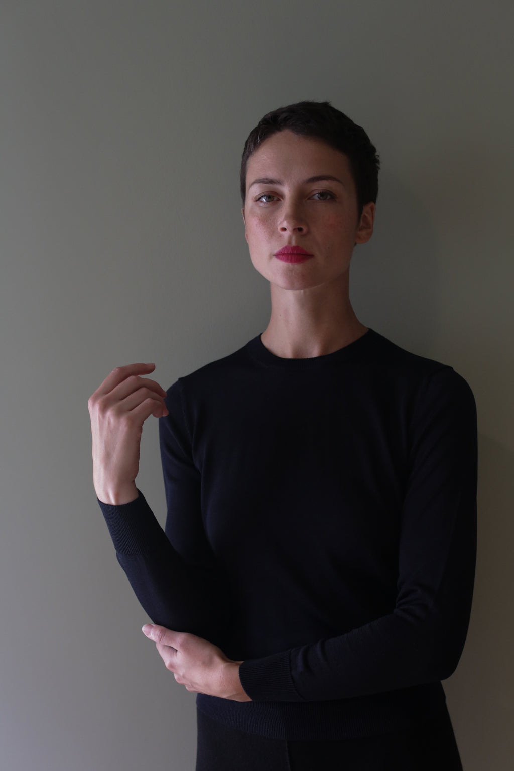 A person wearing an individually knitted, long-sleeved black Washable Silk Crewneck.