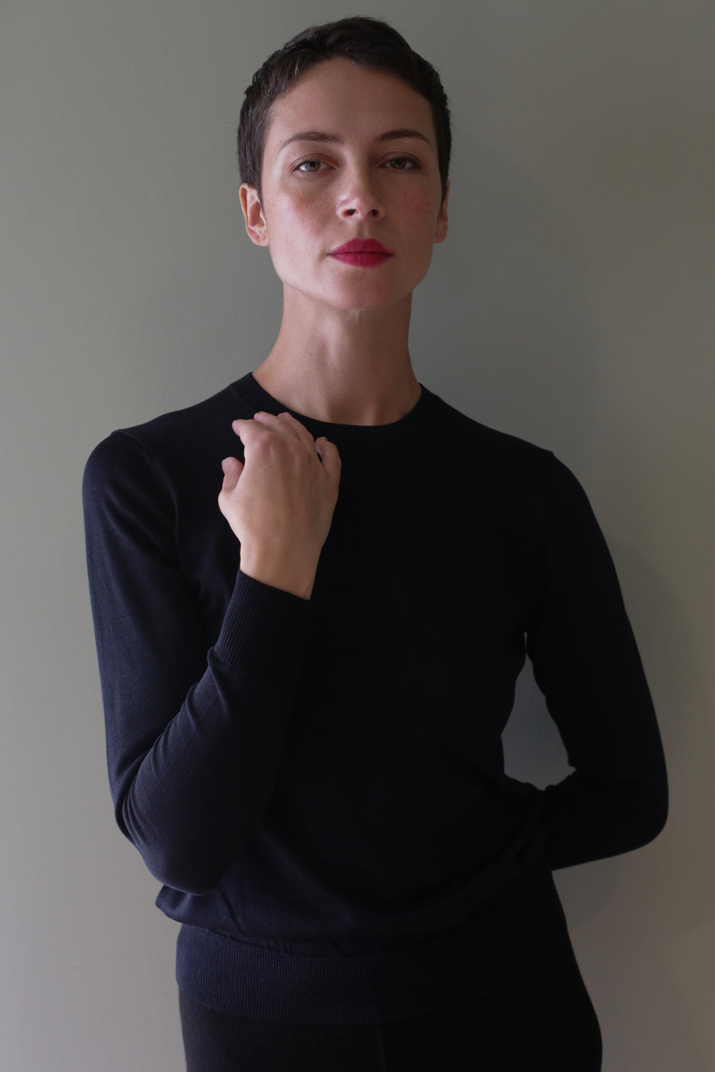 A person wearing an individually knitted, long-sleeved black Washable Silk Crewneck.