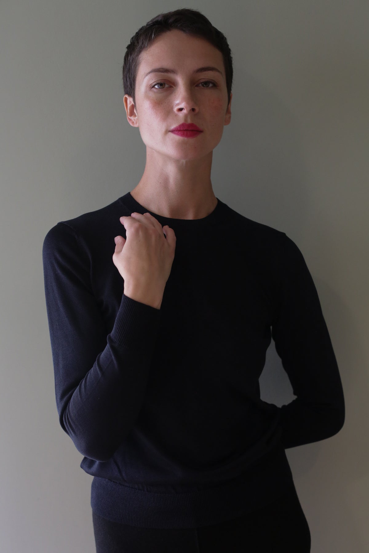 A person wearing an individually knitted, long-sleeved black Washable Silk Crewneck.