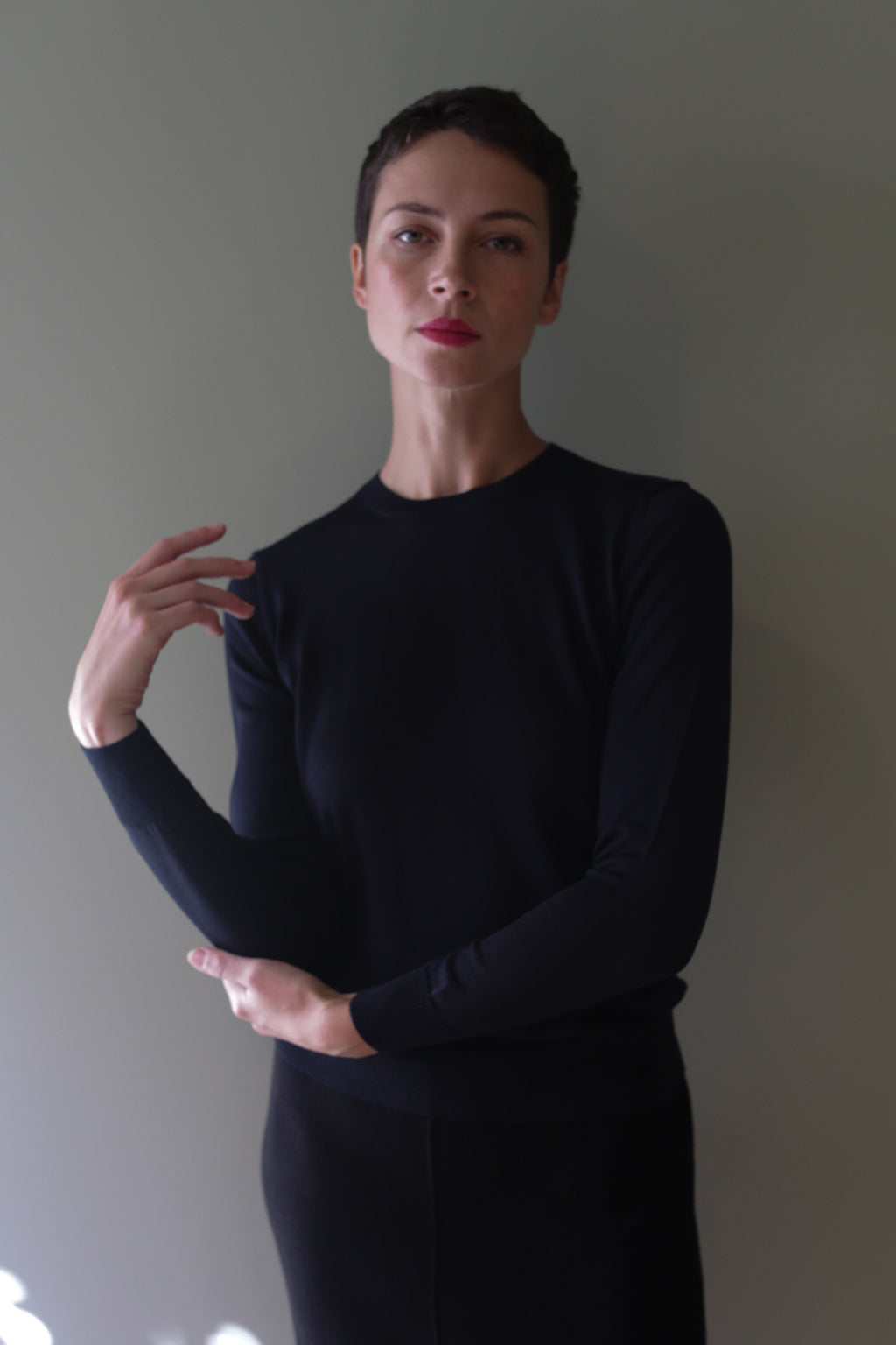 A person with short hair wearing a long-sleeved, black Washable Silk Crewneck.