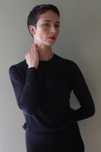 Load image into Gallery viewer, A person wearing a long-sleeved, black Cropped Silk Crewneck | Blue Black shirt with a cropped hem.