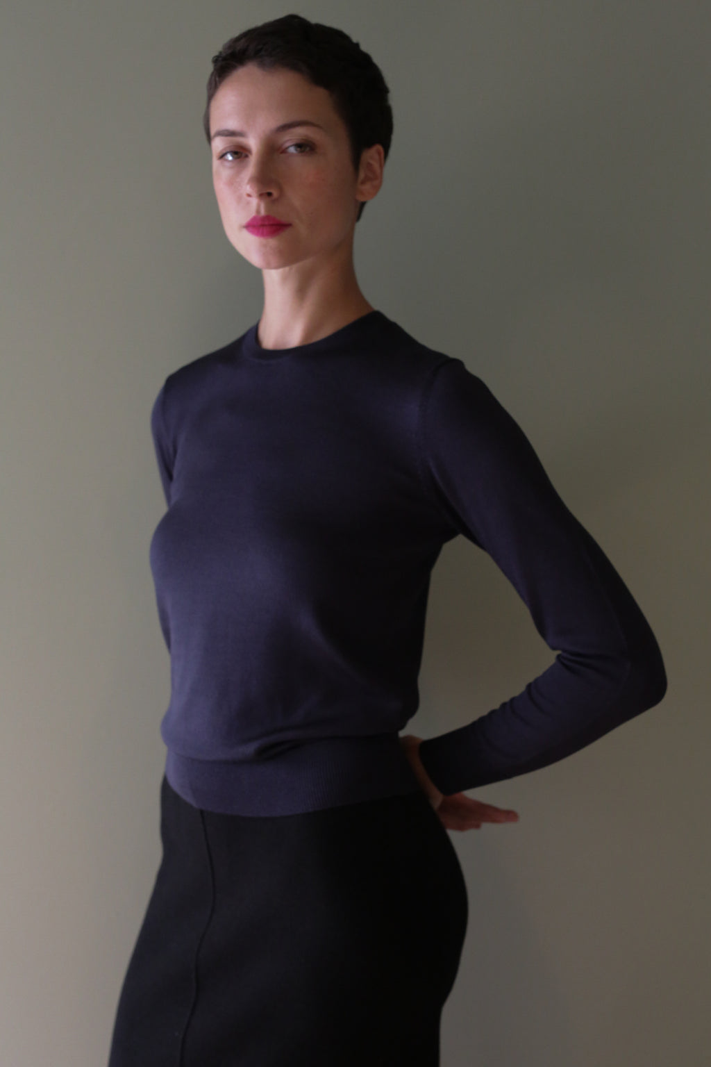 A person wearing a long-sleeved, cropped Navy Washable Silk Crewneck sweater.