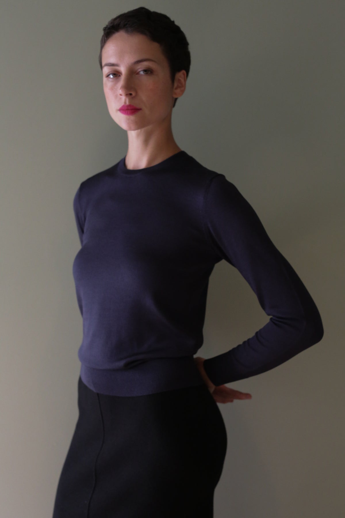 A person wearing a long-sleeved, cropped Navy Washable Silk Crewneck sweater.
