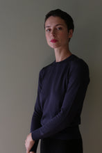 Load image into Gallery viewer, A person wearing a navy blue, long-sleeved Cropped Silk Crewneck sweater with a cropped hem.