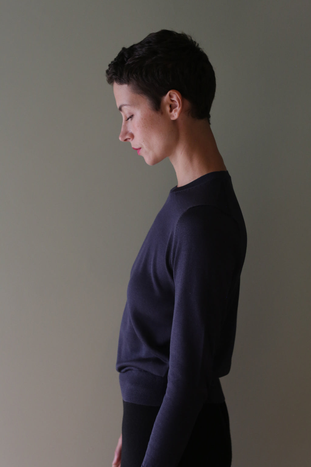 Side profile of a person wearing a navy Washable Silk Crewneck in a cropped, 100% silk style.