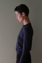 Load image into Gallery viewer, A person wearing a long-sleeved, navy blue Cropped Silk Crewneck from the side.