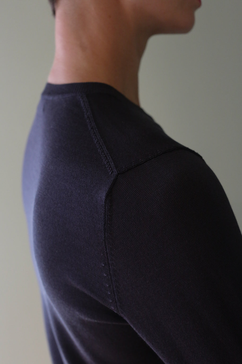 Close-up profile of a person wearing a dark navy Washable Silk Crewneck with raglan sleeves.