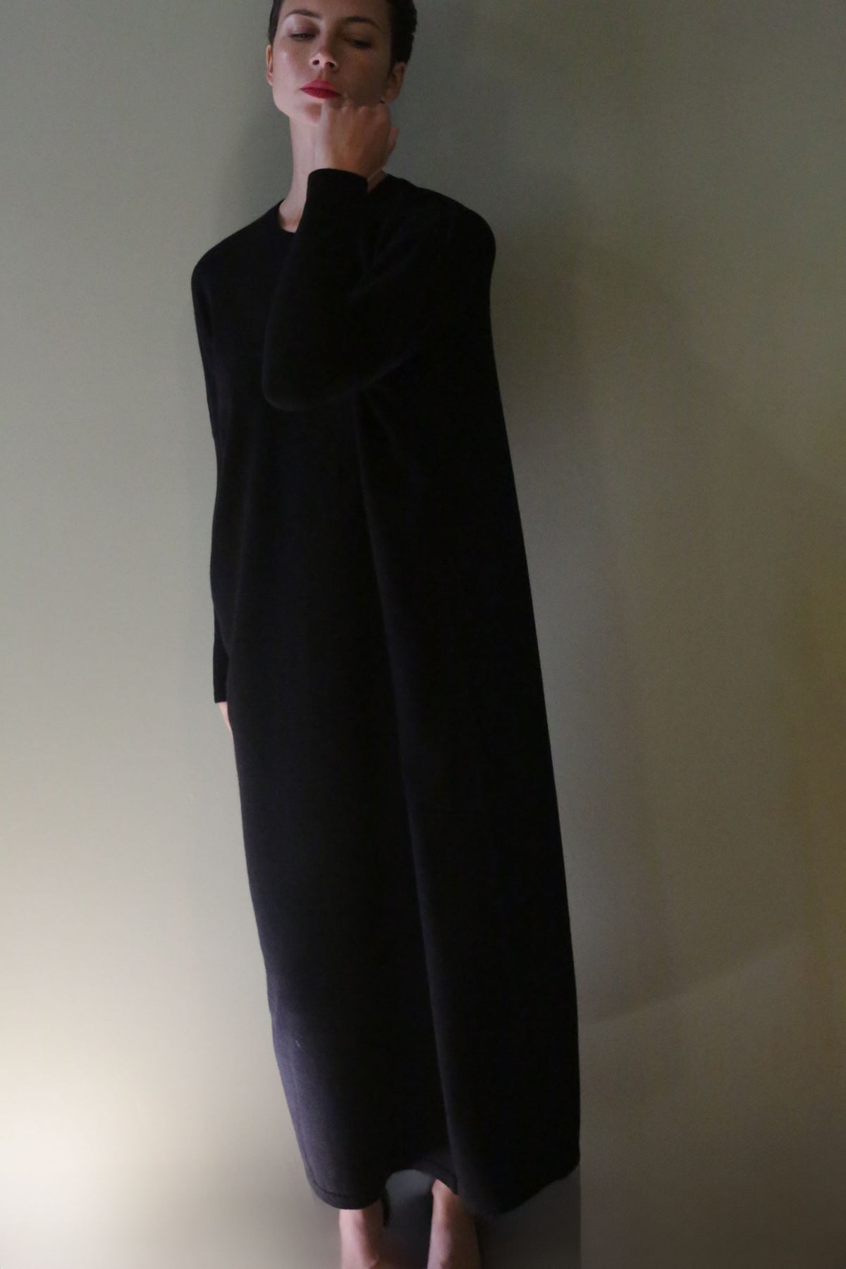 A person wearing a long-sleeved, floor-length black Cashmere Sweater Dress.