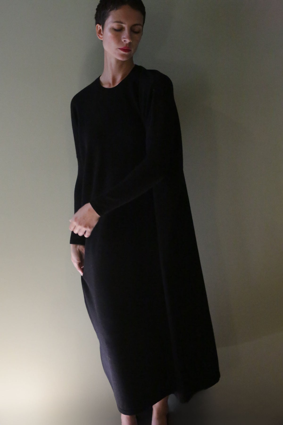 A person wearing a long-sleeved, black, ankle-length Cashmere Sweater Dress.