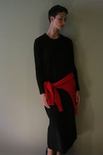 Load image into Gallery viewer, A woman wearing a black Cashmere Sweater Dress with a red sweater tied around her waist.