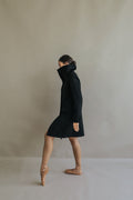 A person in a navy Stamford Long straight-cut cashmere coat and ballet slippers stands on pointe in profile.