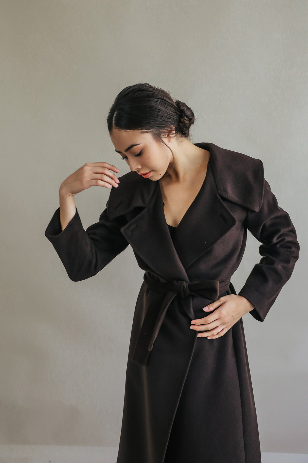 A woman wears the Malvern | Brown, a long brown cashmere wrap coat with wide lapels and a belt.