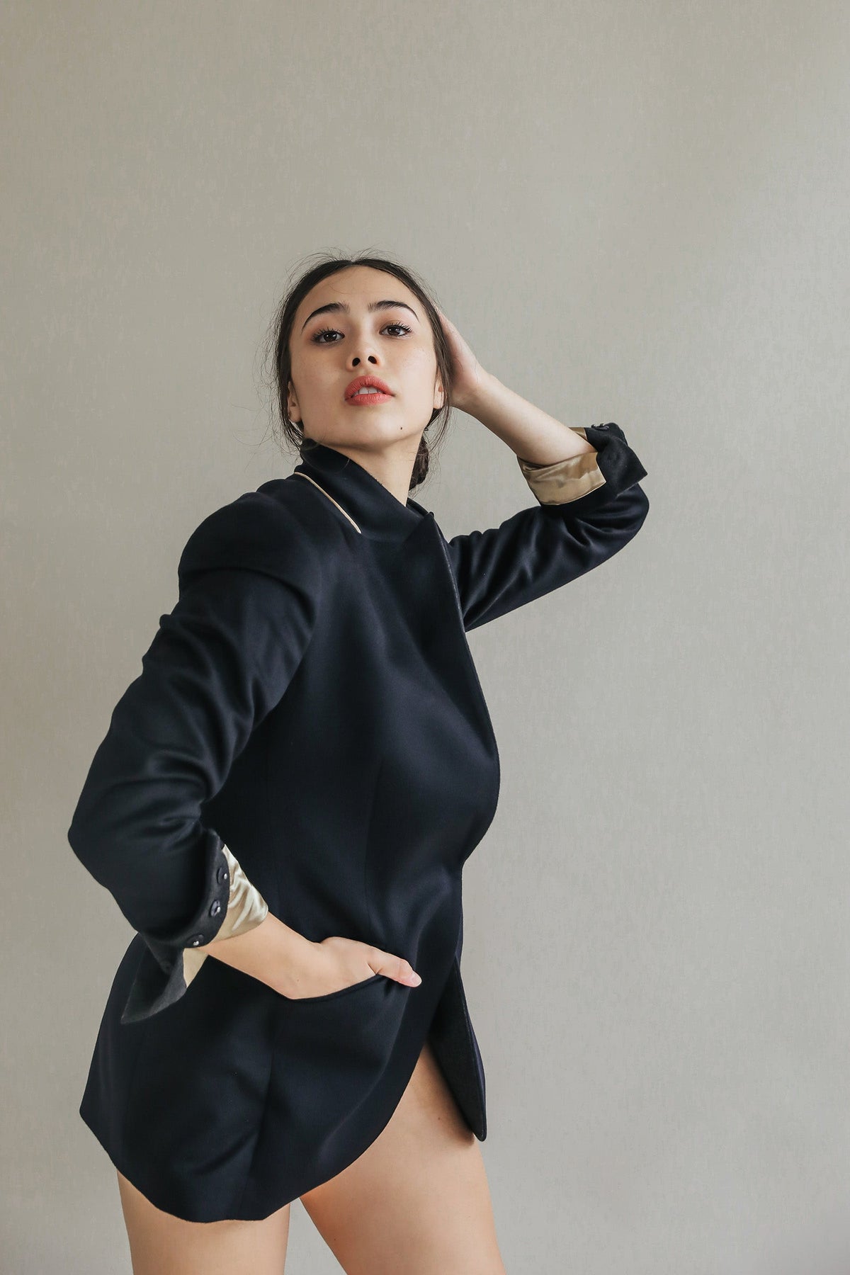 A person posing in a Sloane | Taupe / Black equestrian length black blazer with tan-colored sleeve linings.