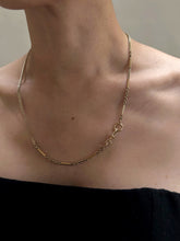 Load image into Gallery viewer, A person wearing an off-the-shoulder black top and an Antique 14K Gold Bar and Link Chain c.1900 with a detailed clasp, complemented by a 12K Flat Curb Chain c.1880. The necklace features a combination of elongated and grooved bar links alongside smaller circular links, set against a plain, neutral background.