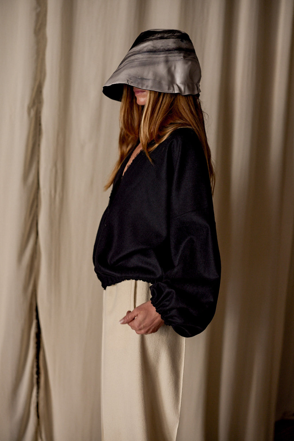 A woman wearing a black shirt and white pants, paired with Noir de Chine crafted from Japanese wool gauze.