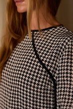 Load image into Gallery viewer, Close-up of a person with long, light brown hair wearing a Qipao Blouse | Crepe de Chine Houndstooth. The photo captures the right side of the person’s face and upper torso, highlighting the luxurious texture and intricate design of the fabric.