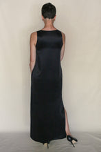 Load image into Gallery viewer, A person with short hair wears the sleeveless, long black Ink Stone Dress, facing away from the camera against a plain light background. The look highlights the elegance of this handmade San Francisco cupro dress.