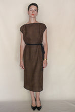 Load image into Gallery viewer, A woman with short hair and a neutral expression models the knee-length Futo Dress Reversible | Xiang Yun Silk Endless Bloom, styled with a black belt, black heels, gold earrings, and a gold wristwatch against a plain background.