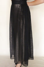 Load image into Gallery viewer, A person wearing the Shoulder Pleat Dress in Linen Leno Black stands against a plain light background, with only the lower torso and legs visible.