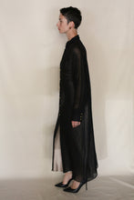 Load image into Gallery viewer, A person with short dark hair stands in profile against a light background, wearing a sheer black dress with gold buttons, black heels, and the Atelier Coat | Linen Lino Black from Lan Jaenicke, handmade in San Francisco.