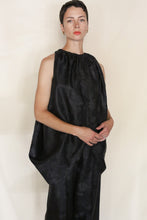 Load image into Gallery viewer, Wearing the Butterfly | Xiang Yun Silk Lingering Fragrance set, a person with short dark hair poses calmly against a plain light background, showcasing the loose-fitting reversible silk top and matching pants.