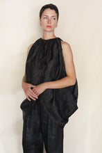 Load image into Gallery viewer, A person with short dark hair wears the Butterfly | Xiang Yun Silk Lingering Fragrance outfit—loose, sleeveless, black with a gathered neckline and wide pants—standing against a plain light background, hands loosely clasped.